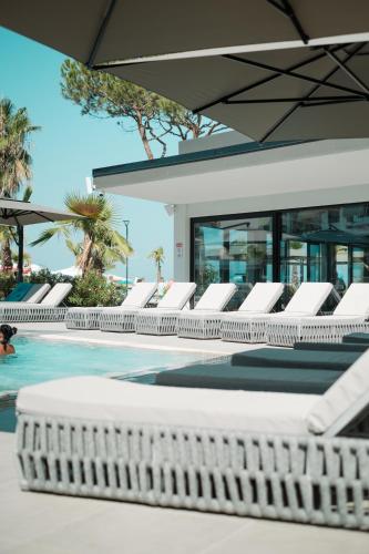 a row of white lounge chairs next to a swimming pool at ApartHotel by Comfort Suites in Golem