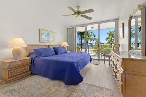 Un dormitorio con una cama azul y un balcón. en St. Pete Isla Bahia Vista 12-245 2BD, en Tierra Verde