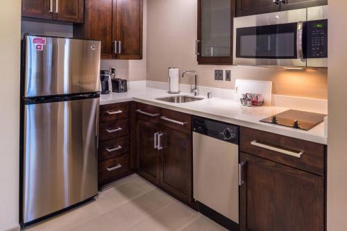 a kitchen with wooden cabinets and a stainless steel refrigerator at Residence Inn by Marriott Seattle University District in Seattle