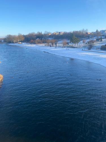 a view of a river with snow on the shore at Biebrzańska Przystań 3 in Goniadz
