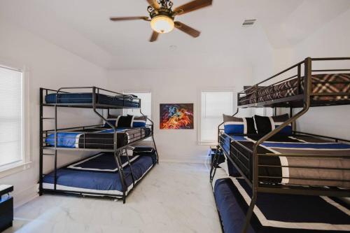 a room with three bunk beds and a ceiling fan at Gorgeous Victorian with Games in San Antonio
