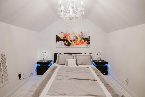 a white bedroom with a bed and a chandelier at Stunning Victorian 3BR Sleeps 10 in San Antonio