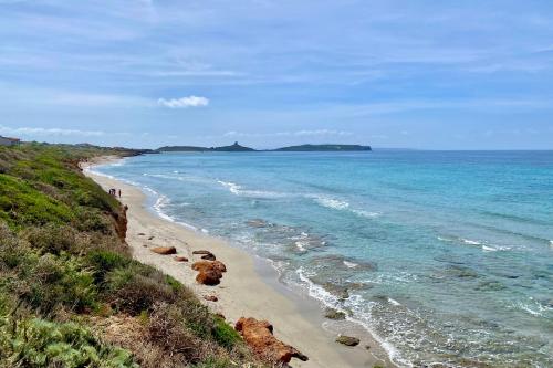 a beach with people walking on the sand and the ocean at Casa Susy in Oristano