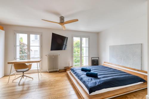 - une chambre avec un lit, un ventilateur de plafond et un bureau dans l'établissement Parisian Loft & Secret Garden, à Paris