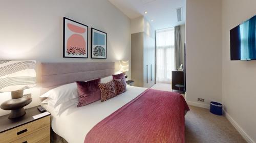 a bedroom with a large bed and a television at Cheval Harrington Court at South Kensington in London
