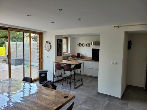 - une cuisine avec une table et quelques tabourets dans l'établissement Maison chaleureuse dans un ancien corps de ferme, à Prémesques