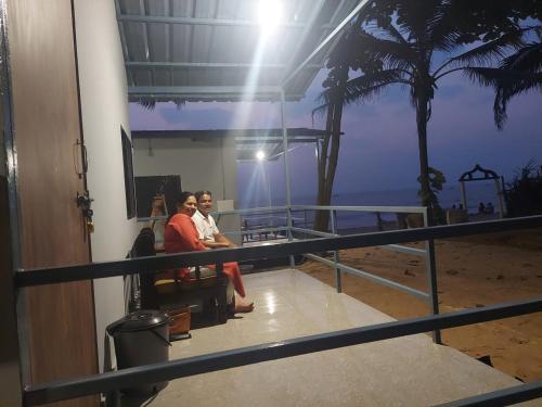 安君纳Ocean View Cottages的两名妇女坐在一个俯瞰海滩的阳台