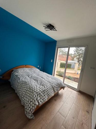une chambre avec un lit et un mur bleu dans l'établissement Charmante maison centre, à Saint-Brévin-lʼOcéan