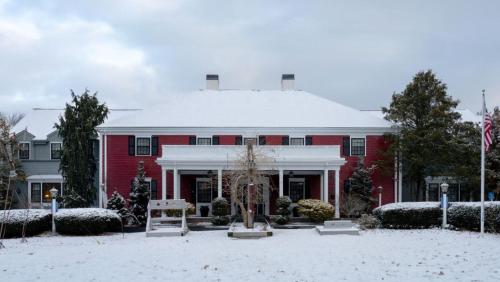 a red building with snow on the ground at Dan'l Webster Inn and Spa in Sandwich