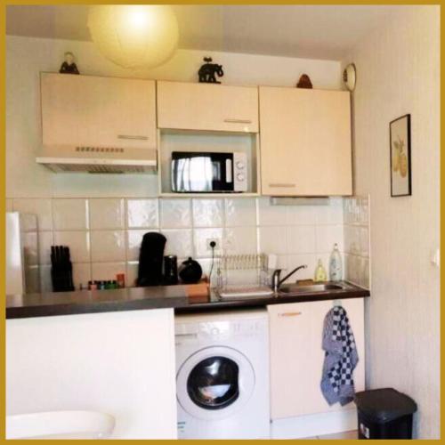 une cuisine avec un lave-linge et un micro-ondes dans l'établissement Le Lodge Central - Parking - Vue Piscine - By Montauban City, à Montauban