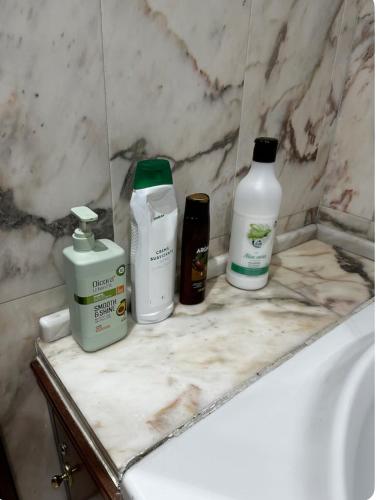 a bathroom counter with three bottles of soap and shampoo at Habitación Centro de Oviedo in Oviedo