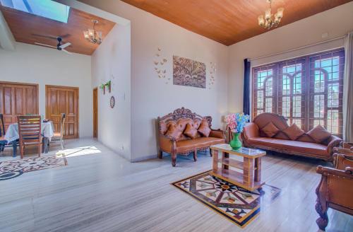 a living room with leather couches and a table at TAJ VILLA Mahabaleshwar ! in Mahabaleshwar