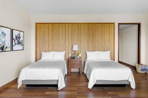 a bedroom with two beds and a table with a lamp at Aurora Anguilla Resort & Golf Club in Rendezvous Beach