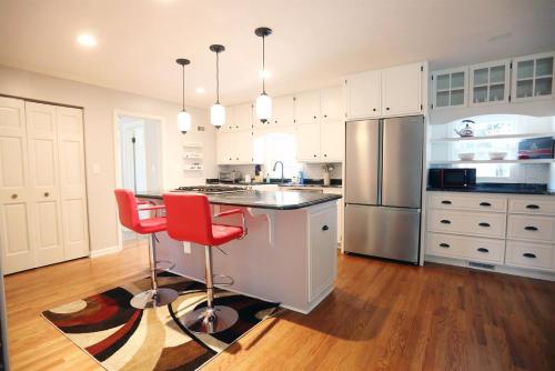 a kitchen with white cabinets and red bar stools at Purdue Bell Tower views, Central WL location, Walk 2 Purdue in West Lafayette