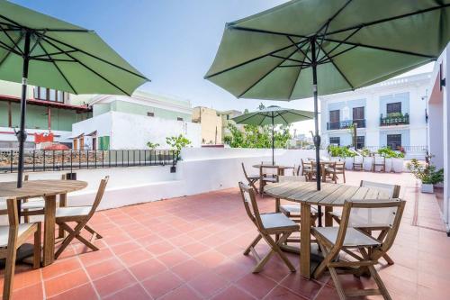 a patio with tables and chairs with umbrellas at Casa Las Ruinas by Stay with Bear in San Juan