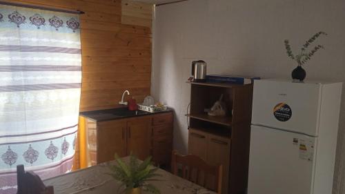 a kitchen with a white refrigerator and a table with a table at Casa céntrica cómoda in Chuí