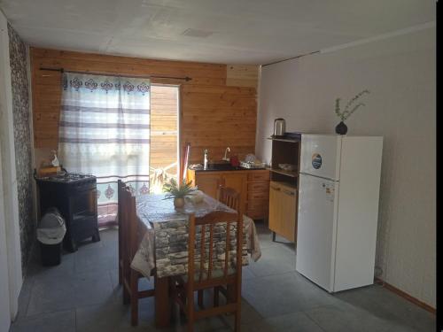 a kitchen with a table and a white refrigerator at Casa céntrica cómoda in Chuí