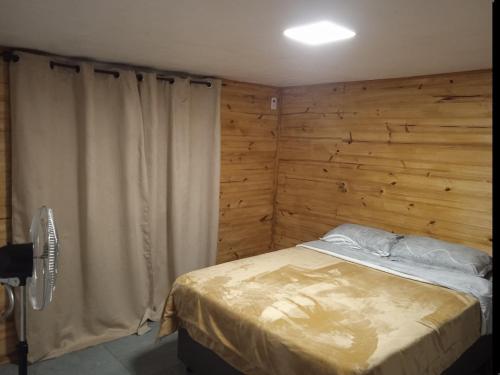 a bedroom with a bed and a wooden wall at Casa céntrica cómoda in Chuí
