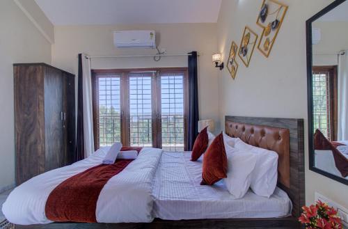 a bedroom with a large bed with white sheets and red pillows at TAJ VILLA Mahabaleshwar ! in Mahabaleshwar