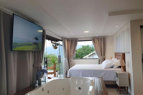 a bedroom with a bed and a tv and a tub at Recanto Pôr do Sol com Hido e lareira in Santo Amaro da Imperatriz