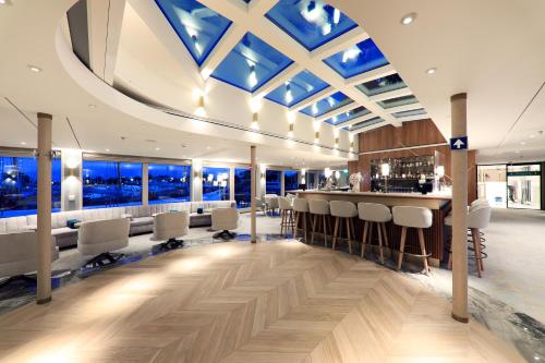 a room with a bar with white chairs and windows at Hotelschiff Lady Diletta in Cologne