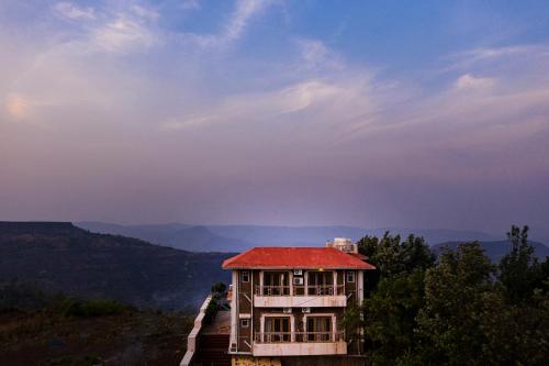 a house with a red roof on top of a mountain at TAJ VILLA Mahabaleshwar ! in Mahabaleshwar