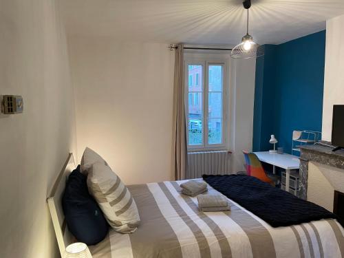 - une chambre avec un lit aux murs bleus et une table dans l'établissement La Petite Fuxéenne, à Foix