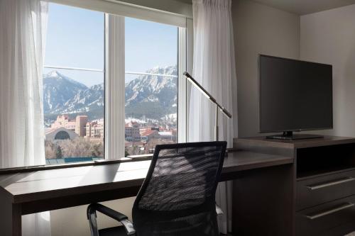 a desk with a monitor and a chair in front of a window at Residence Inn by Marriott Boulder Canyon Boulevard in Boulder