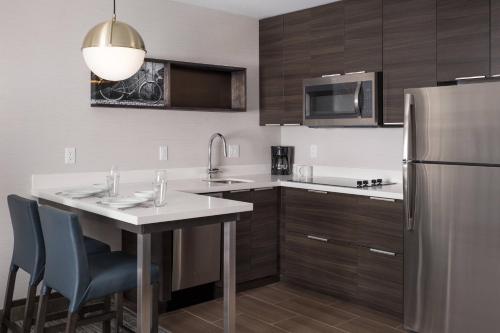 a kitchen with a table and a stainless steel refrigerator at Residence Inn by Marriott Boulder Canyon Boulevard in Boulder