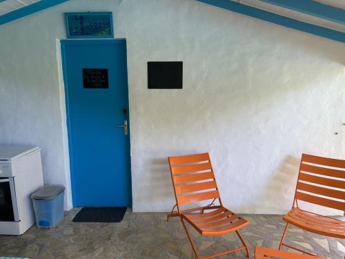 two chairs sitting next to a wall with a blue door at Gwada Rêves in Sainte-Anne