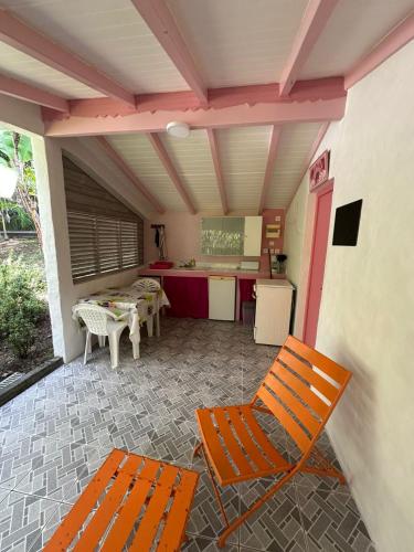 a patio with two orange chairs and a kitchen at Gwada Rêves in Sainte-Anne