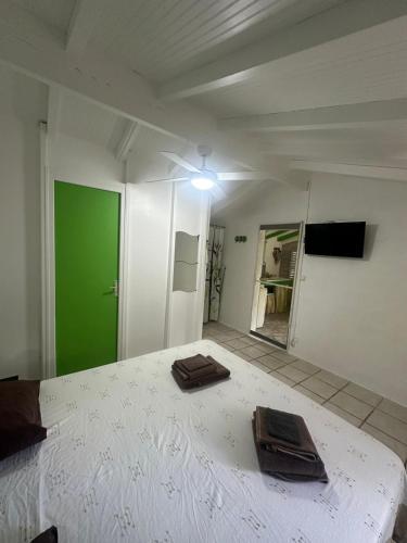 a room with a white bed with a green door at Gwada Rêves in Sainte-Anne