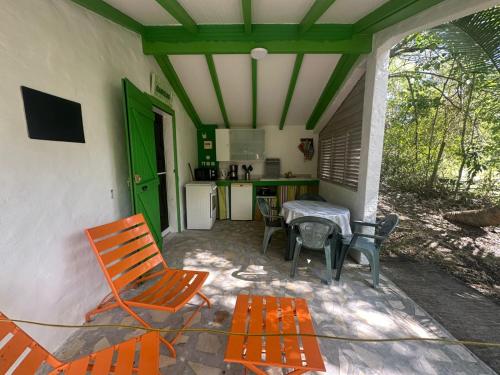 a patio with orange chairs and a table and a kitchen at Gwada Rêves in Sainte-Anne