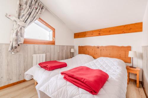 une chambre avec deux lits avec des oreillers rouges dessus dans l'établissement Les Balcons PROCHE PARC NATIONAL VANOISE appartement 3 pieces 8 pers, à Termignon