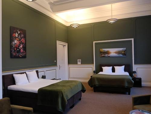 two beds in a room with green walls at The Velvet Lodge in The Hague