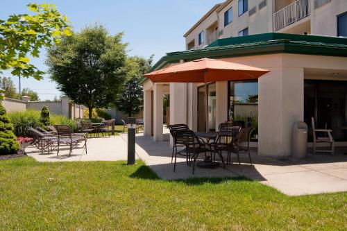 a table and chairs with an umbrella on a sidewalk at Courtyard by Marriott Cincinnati Airport in Erlanger