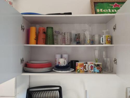 a cupboard filled with plates and cups and dishes at Apartamento Duplex na praia de Salinas RS in Cidreira