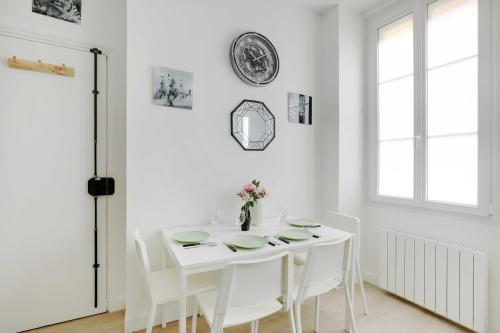 une salle à manger blanche avec une table blanche et des chaises blanches dans l'établissement Cosy Apartement in heart of Batignolles, à Paris