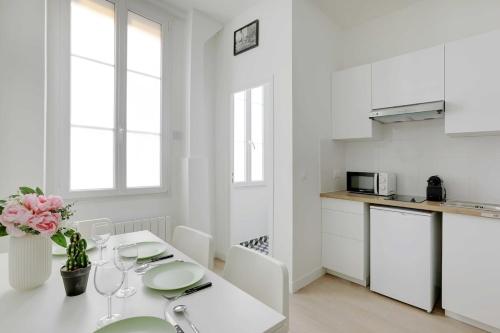 - une cuisine blanche avec une table et des placards blancs dans l'établissement Cosy Apartement in heart of Batignolles, à Paris