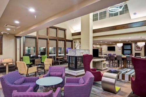 a lobby with purple chairs and tables and a fireplace at Residence Inn by Marriott Hamilton in Hamilton