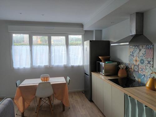 une petite cuisine avec une table et un réfrigérateur dans l'établissement Tregastel 300m des plages, à Trégastel