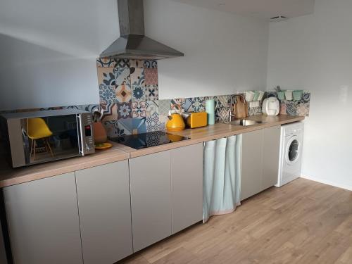 une cuisine avec des armoires blanches et un micro-ondes dans l'établissement Tregastel 300m des plages, à Trégastel