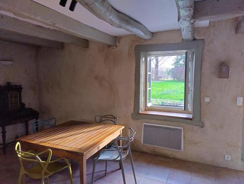 a dining room with a wooden table and a window at Petite Maison à côté de la Forêt de Rennes in Betton