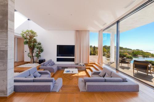 - un salon avec des canapés, une télévision et des portes en verre dans l'établissement Villa SUNSET- 5 chambres, piscine et vue mer, à Porticcio