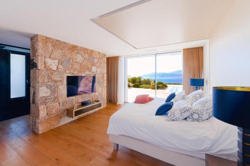 une chambre avec un lit avec un mur en pierre dans l'établissement Villa SUNSET- 5 chambres, piscine et vue mer, à Porticcio