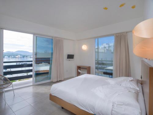 a bedroom with a bed and a large window at Es Mitjorn Hotel in San Antonio