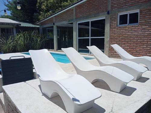 a row of white lounge chairs next to a pool at Complejo Los Gringos in Villa Ciudad de America