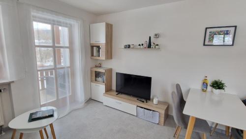 a white living room with a television and a table at Ferienwohnung Grenzenblick in Bayerisch Eisenstein