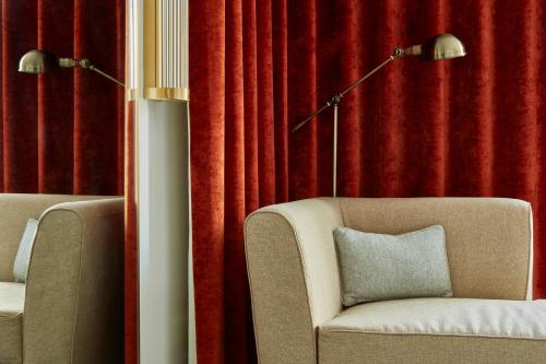a living room with red curtains and a chair and a lamp at Hotel Indigo London - 1 Leicester Square by IHG in London