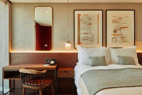 a bedroom with a bed and a desk with a mirror at Hotel Indigo London - 1 Leicester Square by IHG in London